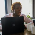 Person sitting at a desk behind a black Surface laptop