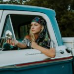 photography of woman holding side mirror in white and green 2-door pickup truck