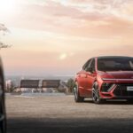 a red car parked next to a park bench