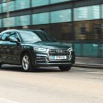 a black car driving down a street next to a tall building
