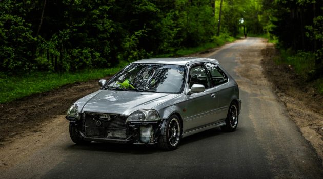 A damaged silver car parked on a forest road in Belarus. Ideal for automotive and transportation themes.