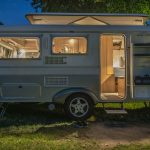 white and brown camper trailer beside tree