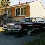 Maroon vintage car parked in front of brick house