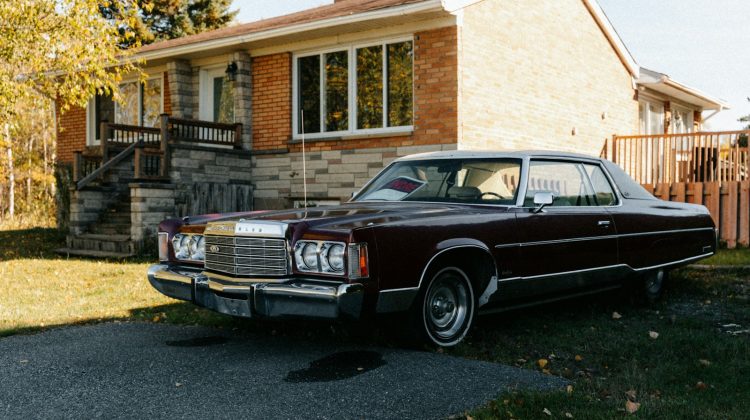 Maroon vintage car parked in front of brick house