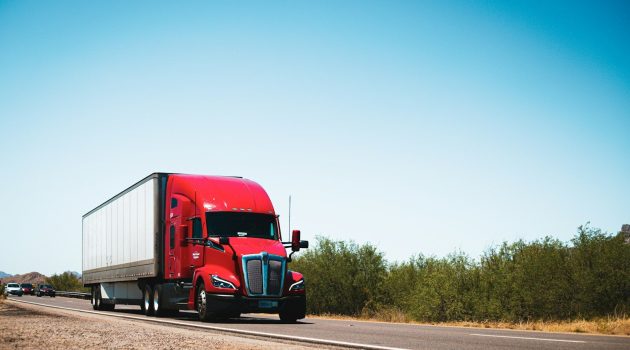 A red semi truck driving down a country road