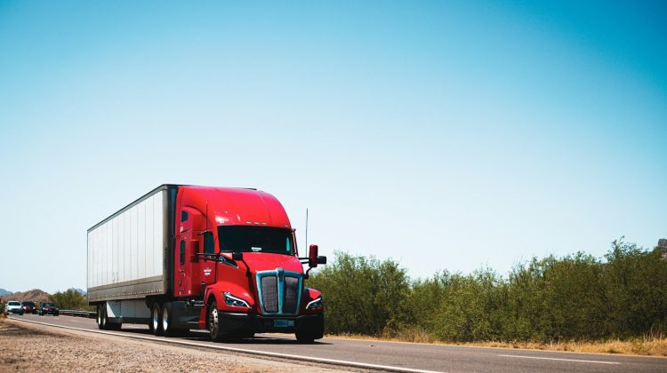 A red semi truck driving down a country road